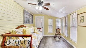 A bedroom with a bed, a wooden chair, a ceiling fan, and a window with blinds.