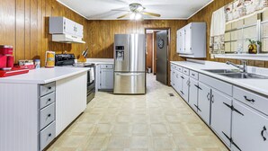 A kitchen with wooden paneling, white cabinets, stainless steel appliances, and a tiled floor.