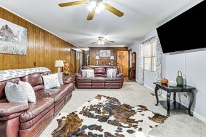 Ein Wohnzimmer mit einer Ledersofa, einem Holzkartonventilator und einem Kuhfellteppich.