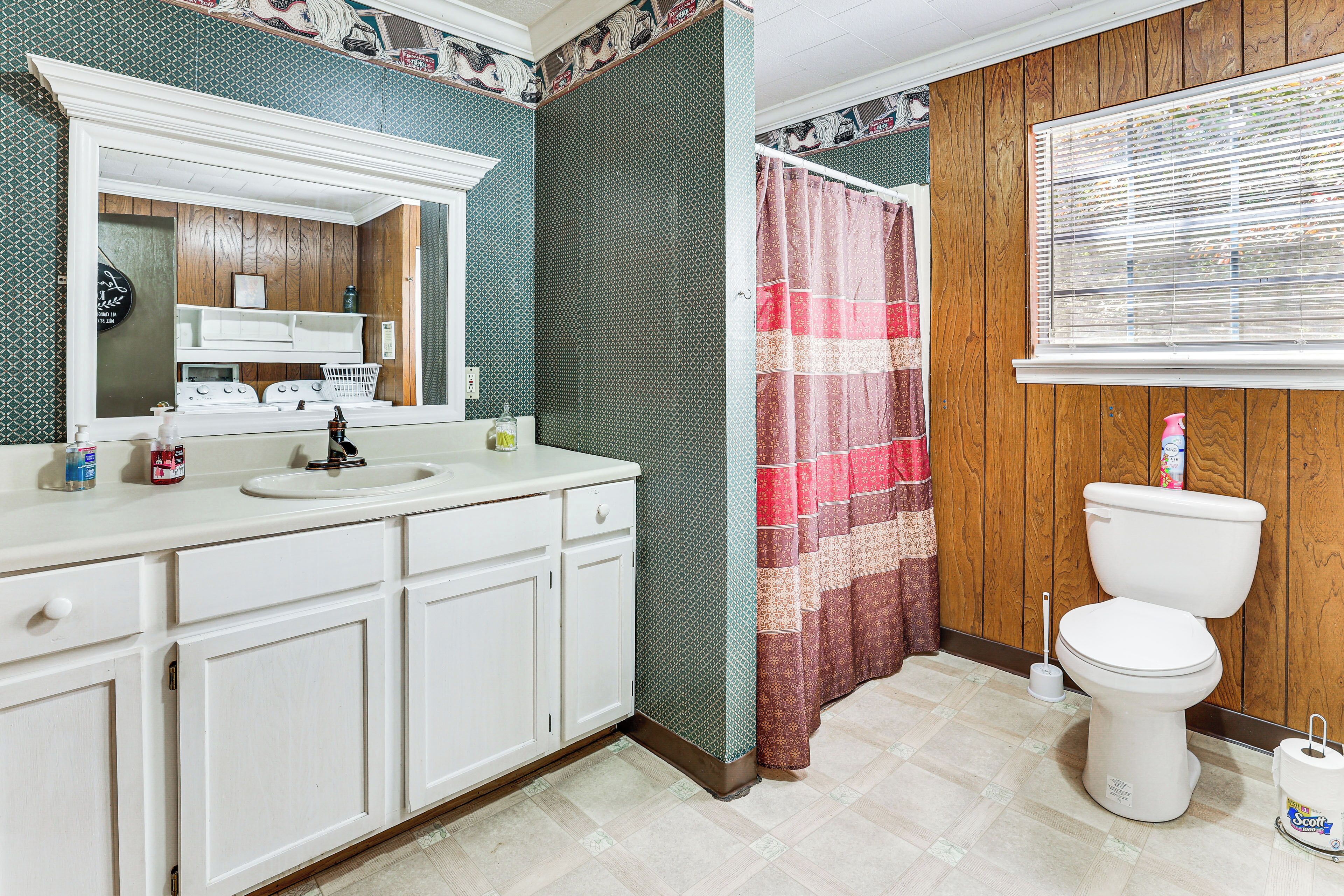 A bathroom with a wooden vanity, a sink, a toilet, and a shower curtain.