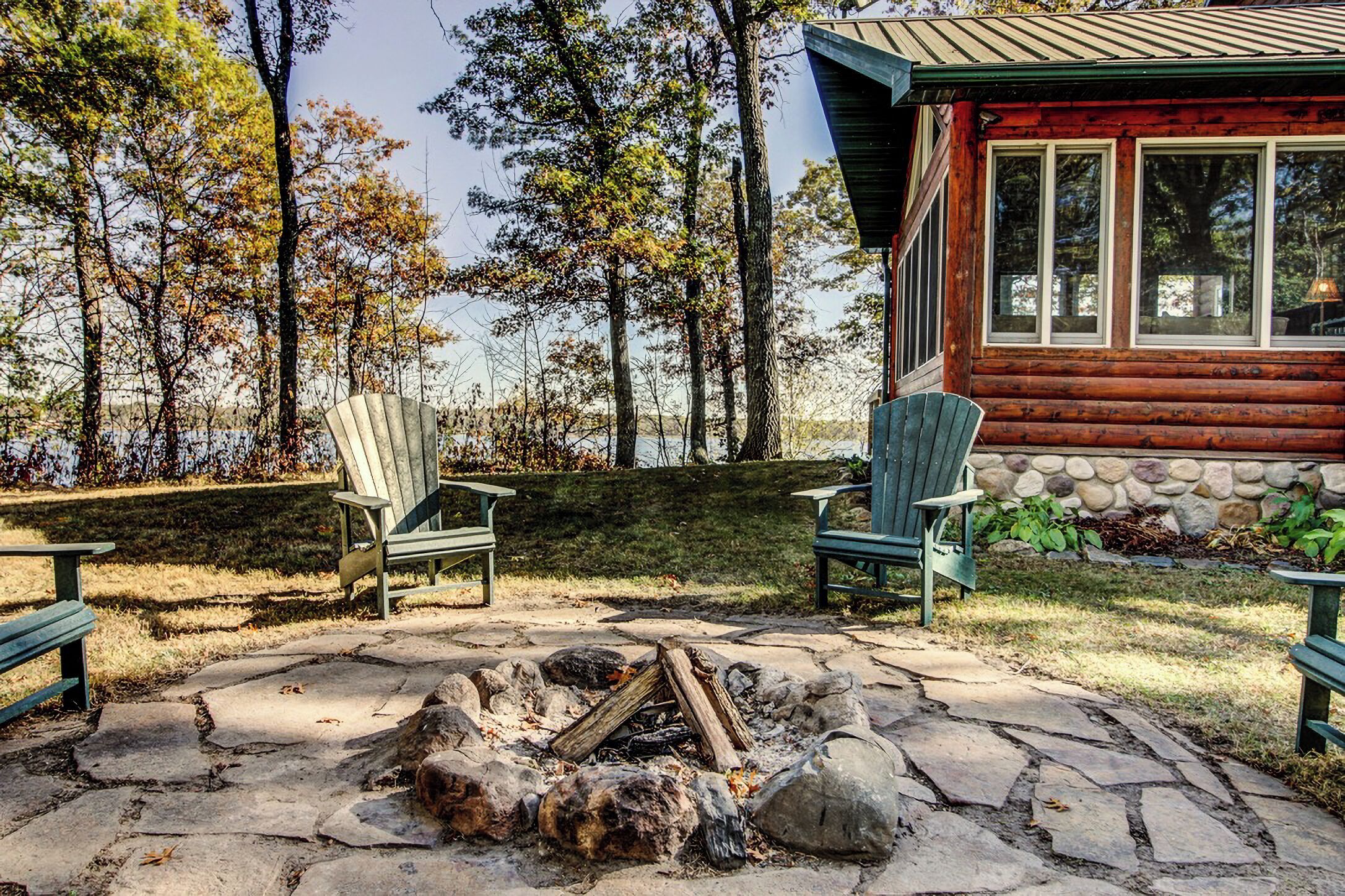 Een blokhut met een vuurplaats van steen en Adirondack-stoelen.