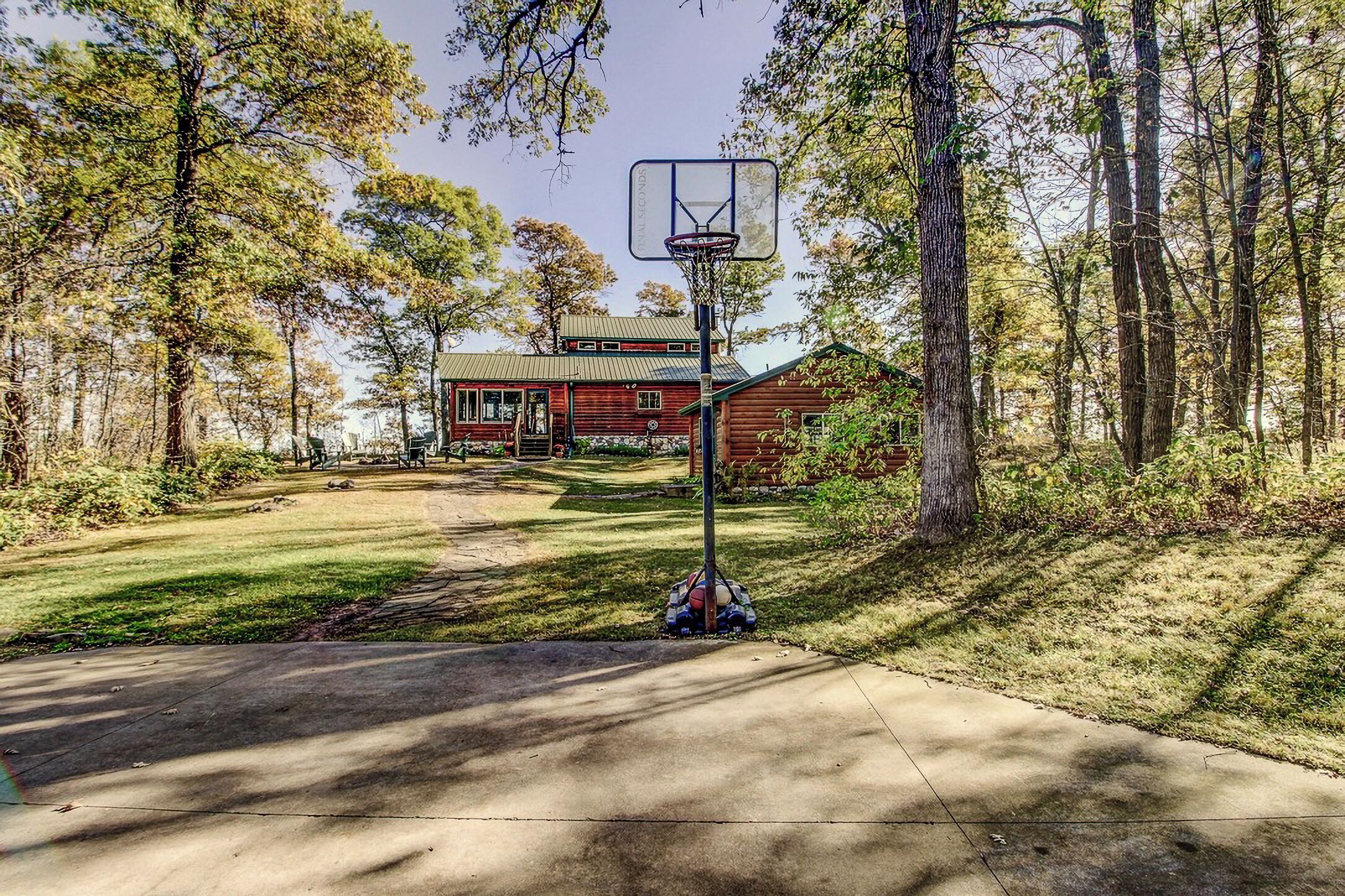 En basketballkurv i et skovområde med et hus i baggrunden.