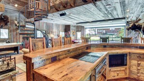 Een rustiek interieur met een houten bar, een spiltrap en dierenkoppen aan de muur.