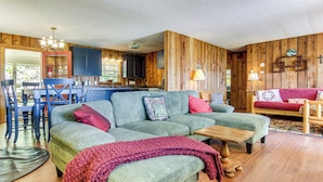 Ein gemütliches Wohnzimmer mit einem grünen Sofa, einem Holzespeisetisch und einer Küchenzeile mit Holzwänden und -schränken.