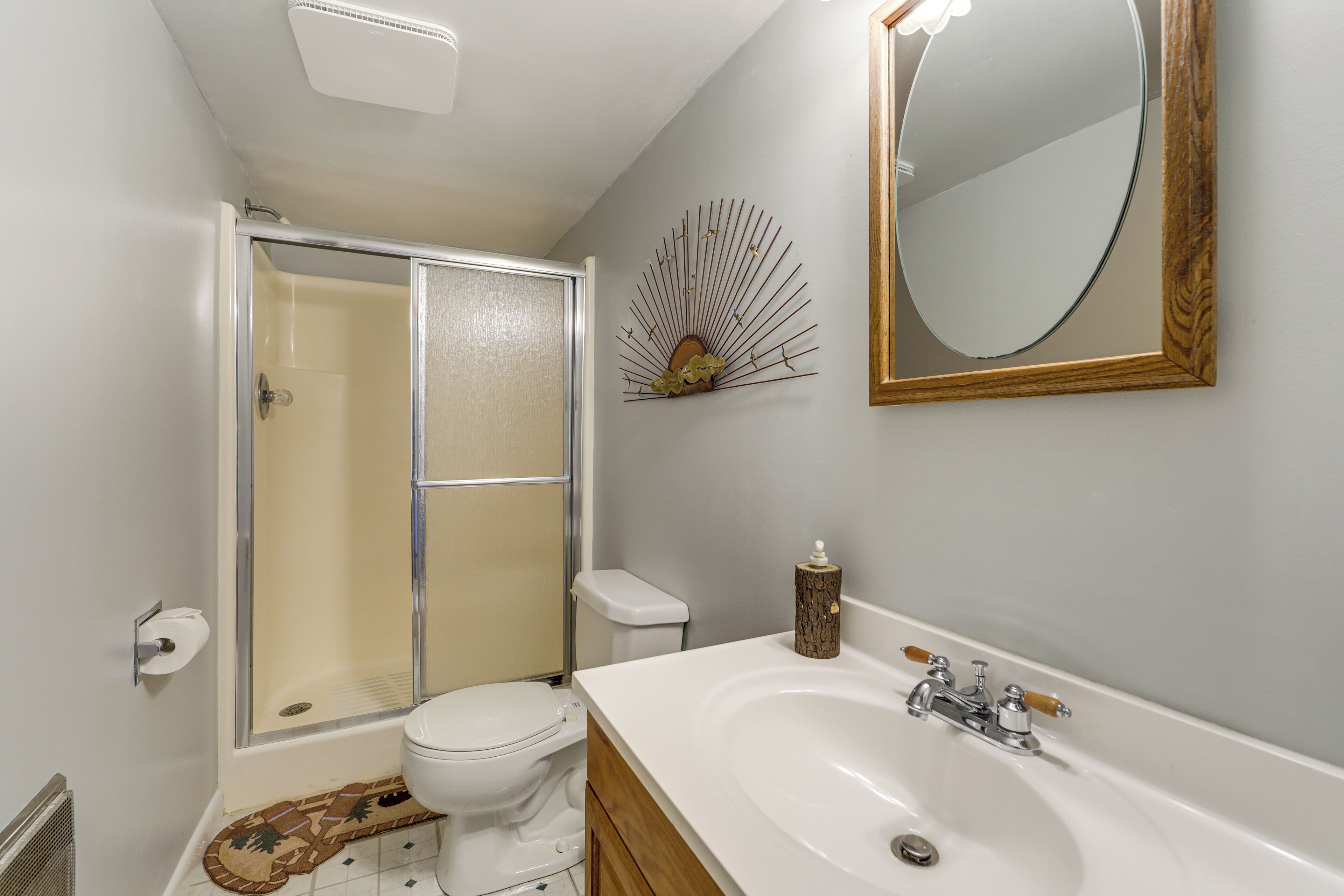 A bathroom with a shower, toilet, sink, and mirror.