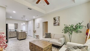 A spacious living area with a sofa, coffee table, and a dining area with a kitchen in the background.
