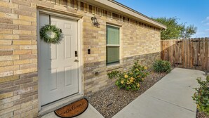 A brick house with a white front door, a window, and a wooden fence.