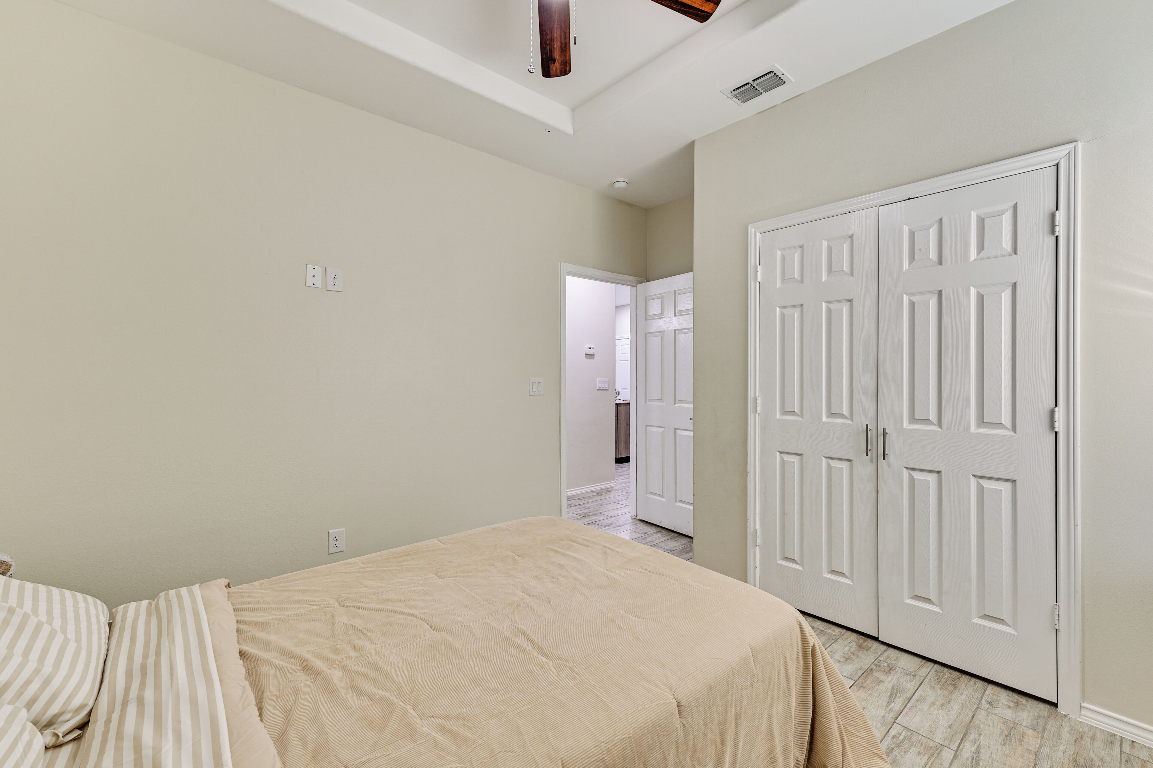 A bedroom with a bed, a wardrobe, and a door leading to another room.