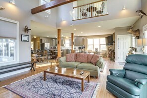 A spacious living room with a green sofa, a leather armchair, and a wooden coffee table.