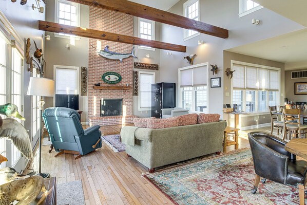 A spacious living room with a fireplace, a large window, and a dining area.