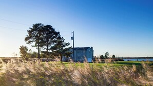 A house with a large lawn and a body of water in the background.