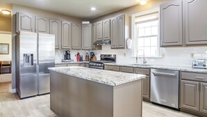 A modern kitchen with stainless steel appliances, a central island, and a large window providing natural light.