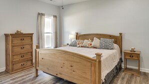 Ein Schlafzimmer mit einem hölzernen Bett, einem Nachttisch, einer Kommode und einem Fenster mit Vorhängen.