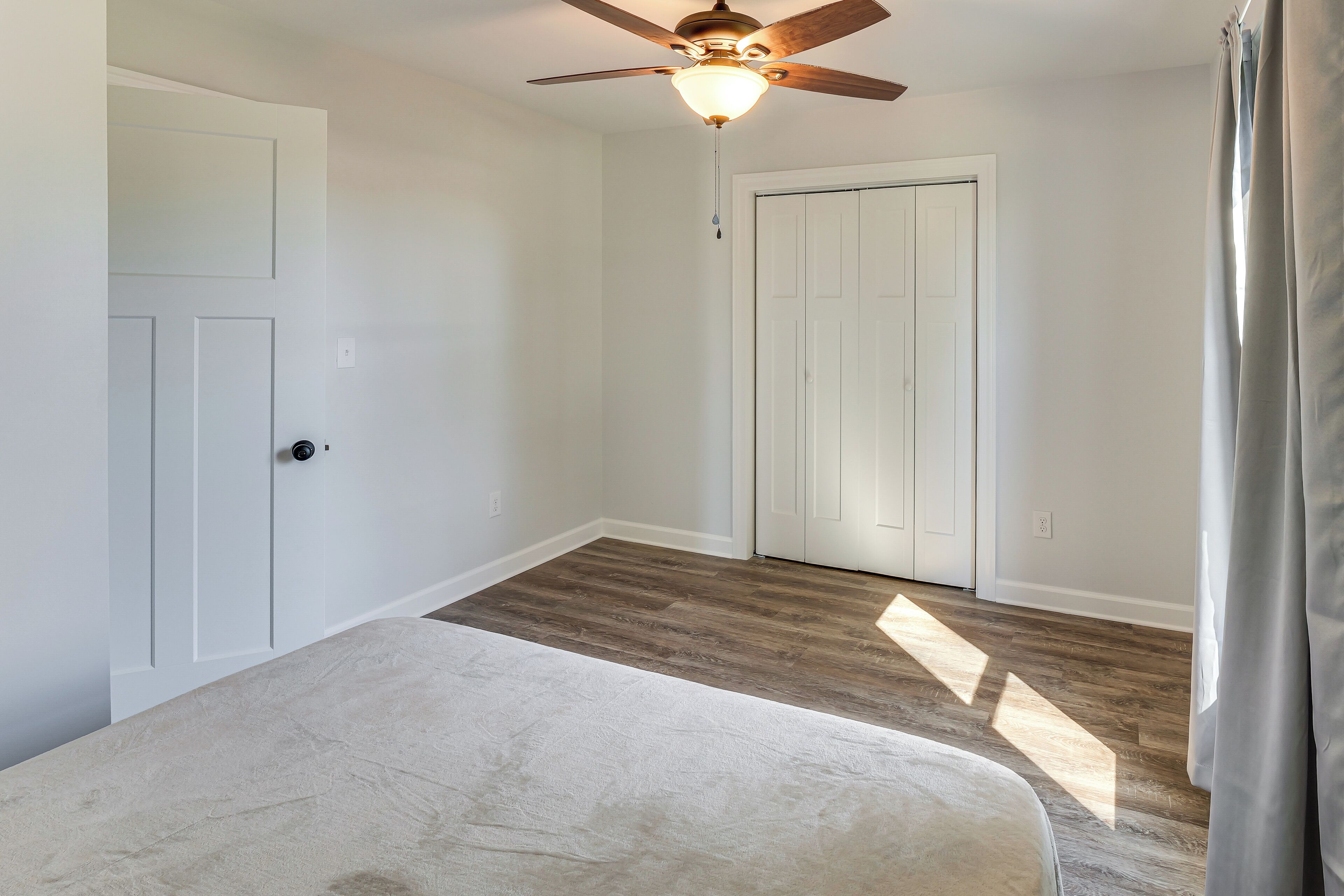 A room with a ceiling fan, a door, and a light fixture.