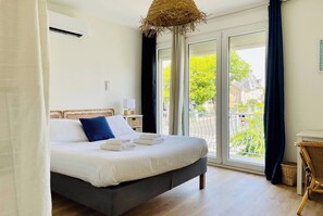 A bedroom with a bed, a window with a view, and a ceiling fan. - L'Escapade Rochelaise, la Genette, LR109 (La Rochelle)