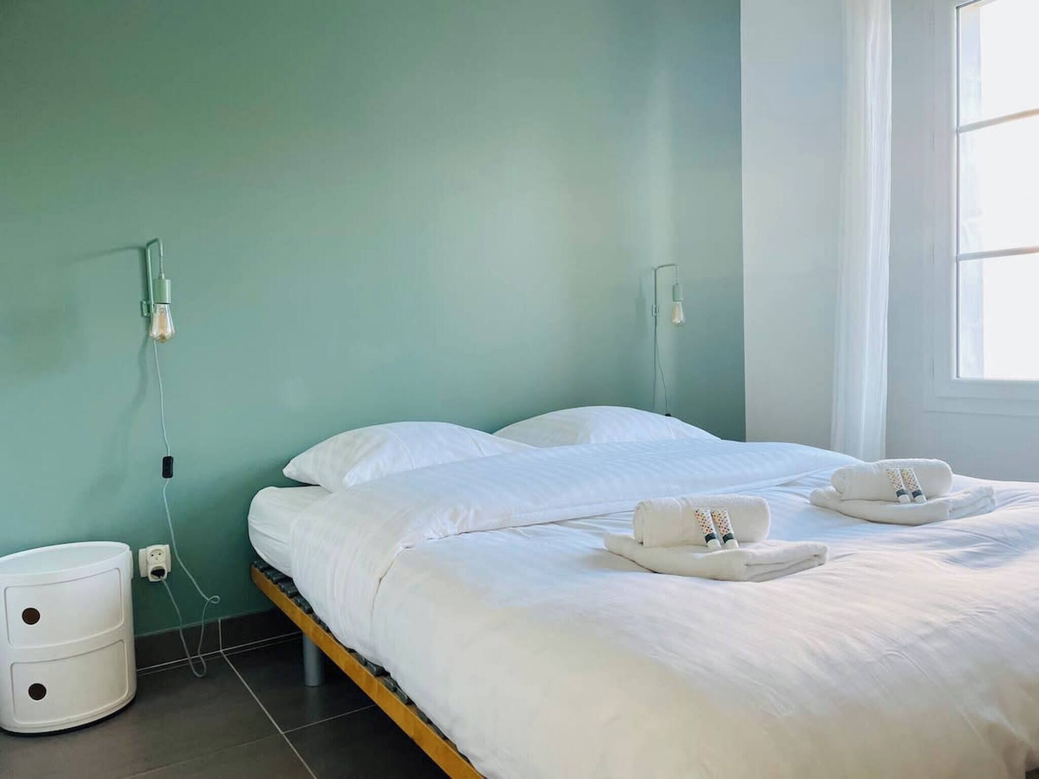 Une chambre d’hôtel avec deux lits, une table de chevet, une lampe et une fenêtre.