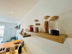 A kitchen with wooden shelves holding glass jars of various contents. - La Petite Genette, LR146 (La Rochelle)