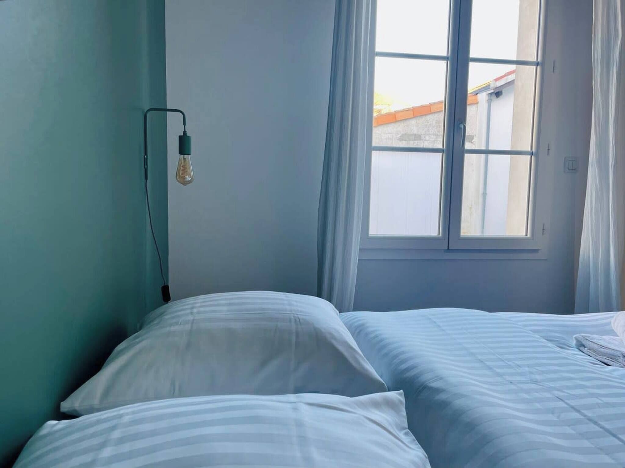 A bedroom with a bed, a window, and a wall socket.