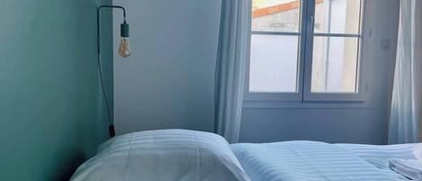 A bedroom with a bed, a window, and a wall socket.
