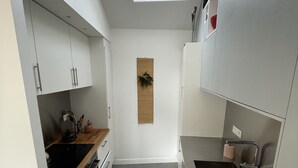 A narrow kitchen with white cabinets, a skylight, a wooden countertop, and a stainless steel sink. - Le bonpland, centre ville, LR122 (La Rochelle)