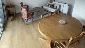 A dining area with a round wooden table, two chairs, a small side table, and a chair with a patterned cushion. - Le bonpland, centre ville, LR122 (La Rochelle)