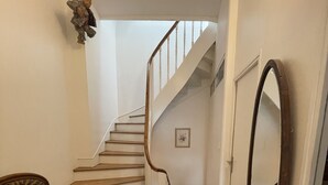 A staircase with wooden steps and white walls, a chair with a zebra pattern, and a large mirror on the wall. - Le bonpland, centre ville, LR122 (La Rochelle)