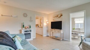 A modern living room with a sofa, TV, and a dining area visible through an open door. - Relax in Hot Tub, Walk to Springs: North Port Home (North Port)