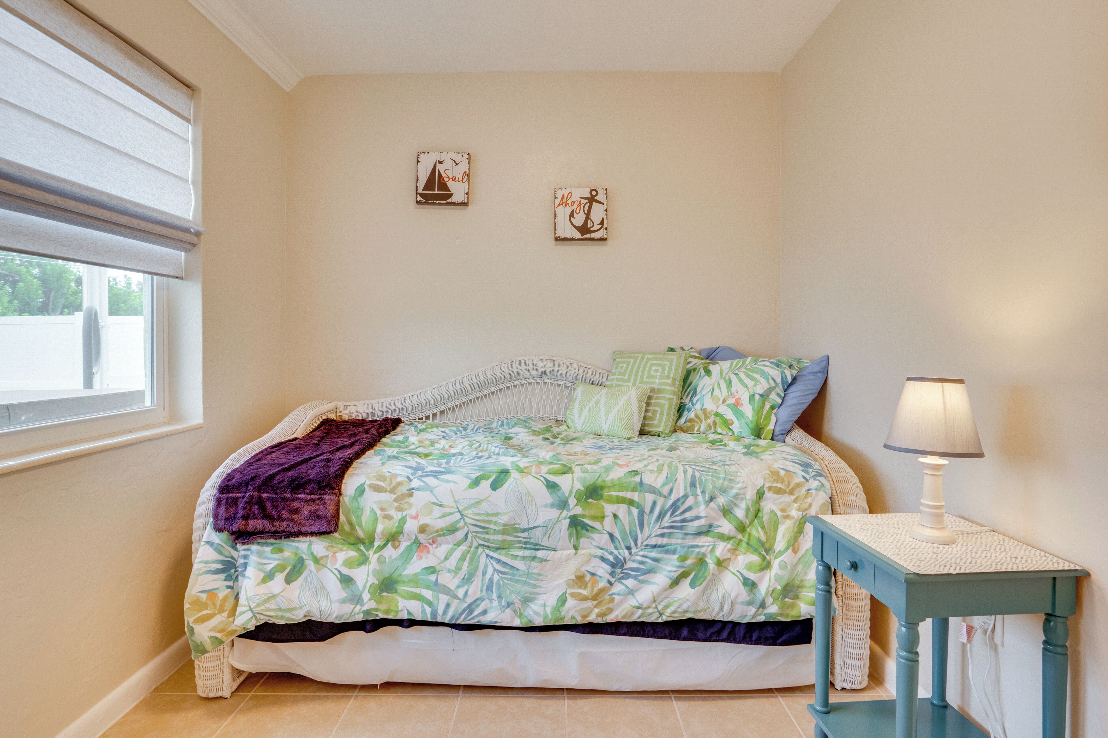 A bedroom with a bed, a nightstand, a lamp, and two wall decorations.
