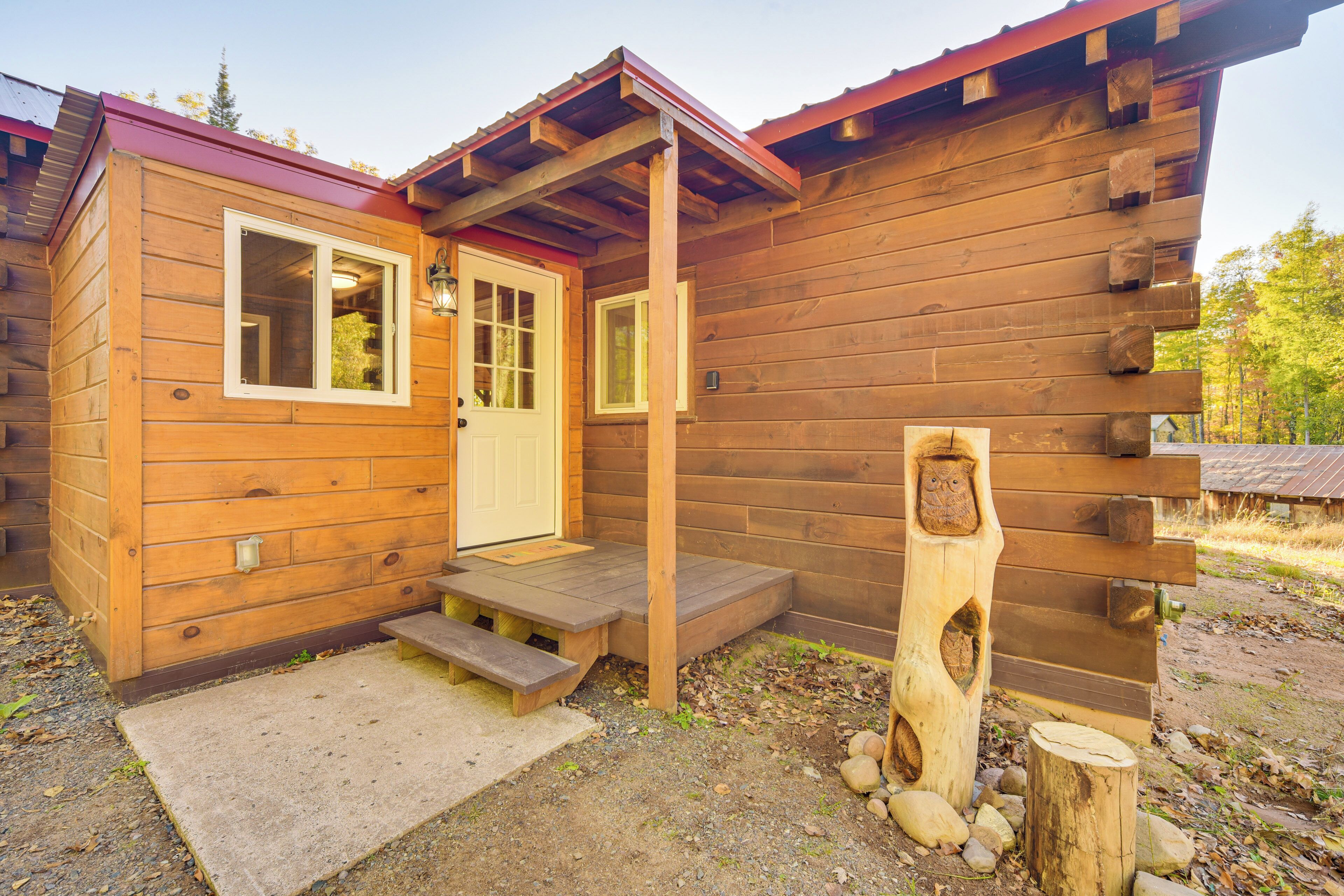 Une cabane en bois avec une porte d’entrée, des fenêtres et une véranda.