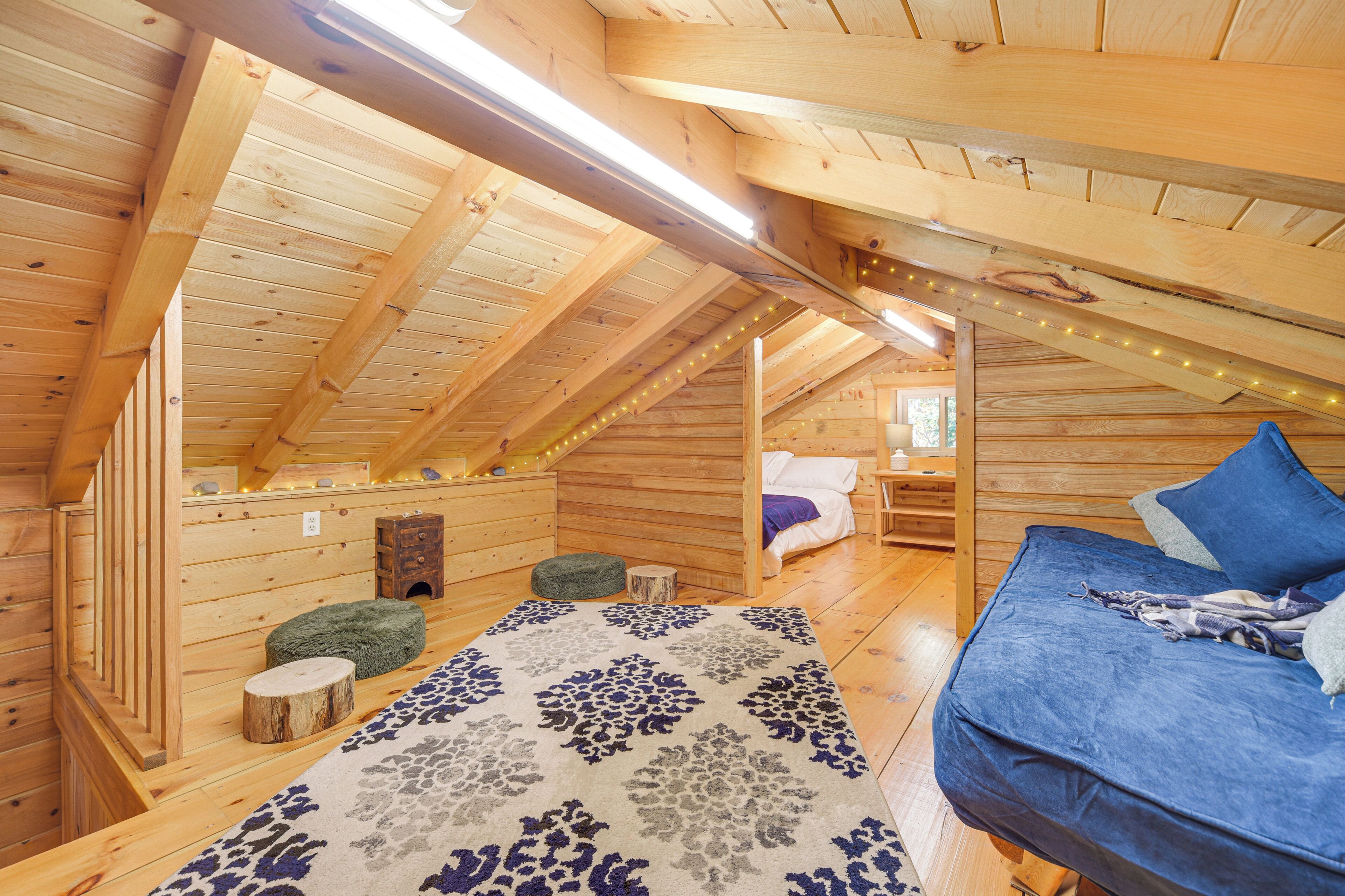 Une cabane en bois avec une chambre à coucher aménagée en mezzanine, un coin salon confortable et une décoration rustique.