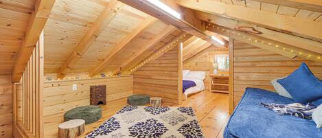 Une cabane en bois avec une chambre à coucher aménagée en mezzanine, un coin salon confortable et une décoration rustique.