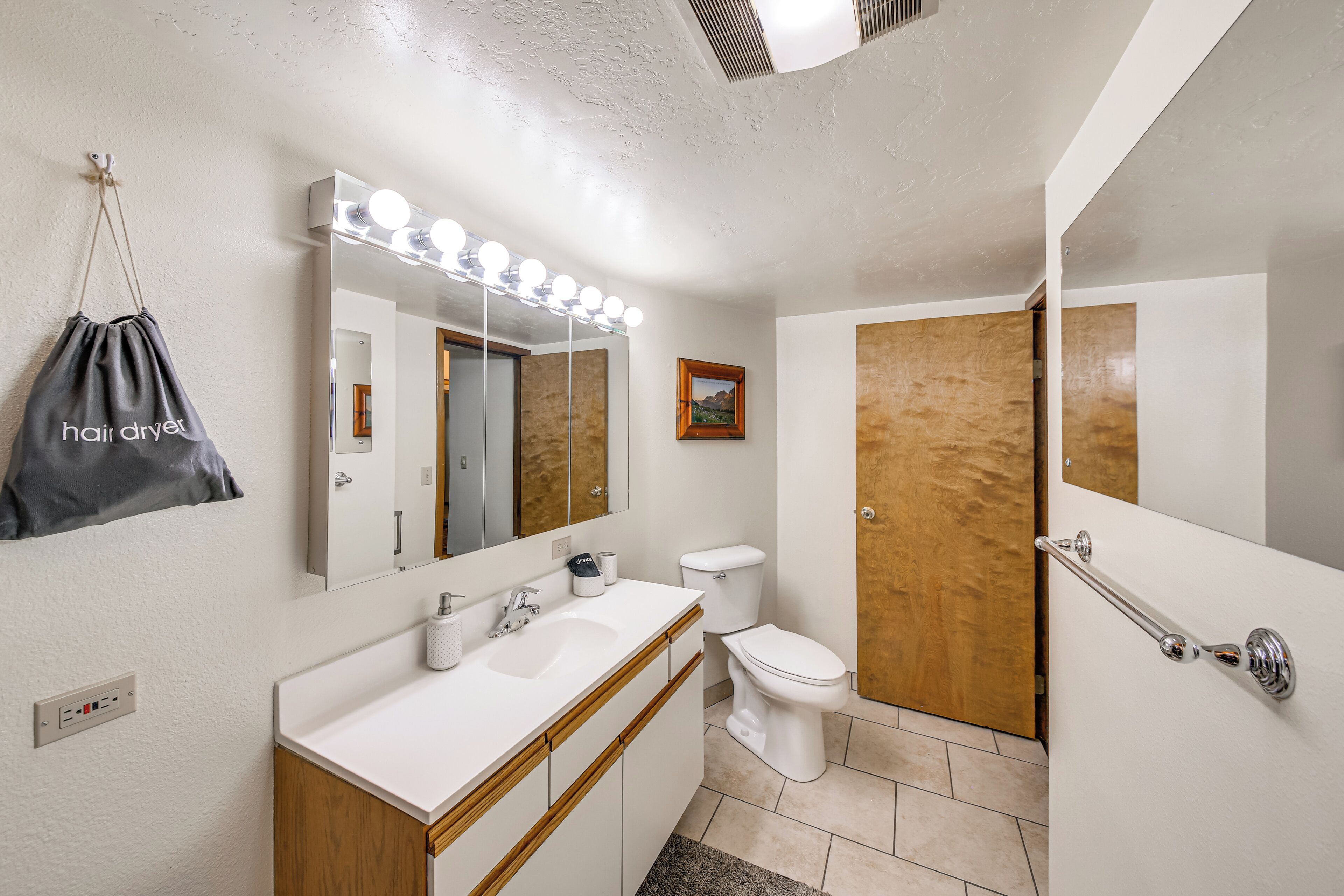 Een badkamer met een wastafel, wasbak, spiegel en toilet.