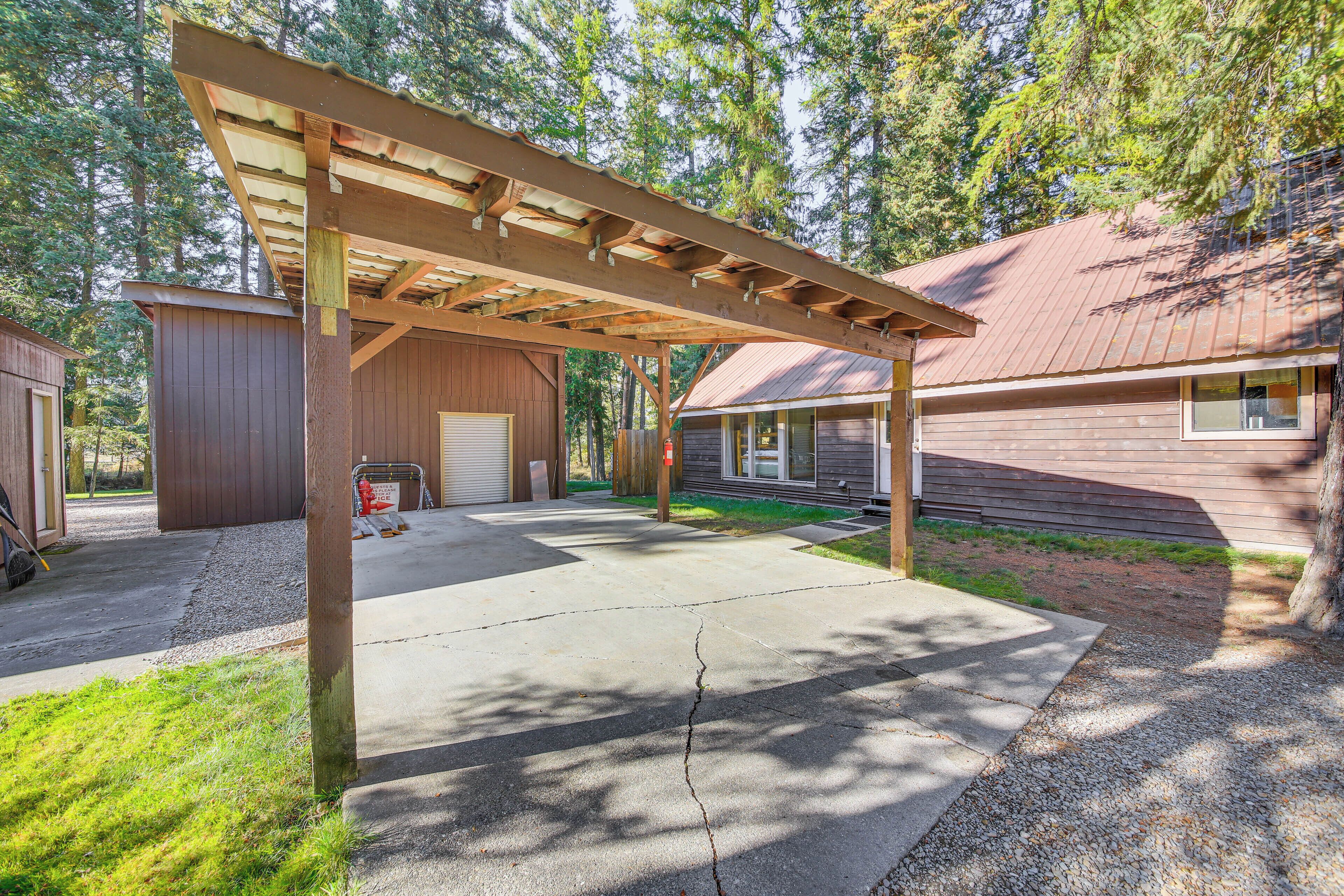 A covered patio area with a concrete floor, wooden pergola, and a garage door.