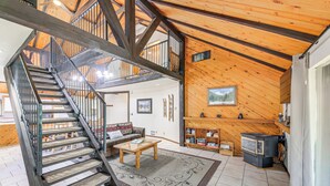 Un amplio espacio habitable con una escalera de madera, una chimenea y una acogedora zona de estar.