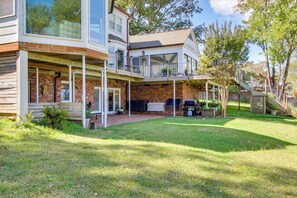 A two-story house with a covered patio, a brick exterior, and a large window overlooking the yard.