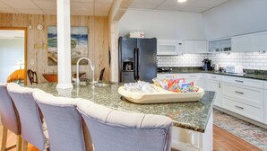 Una cocina moderna con encimera de granito, armarios blancos y un refrigerador negro.