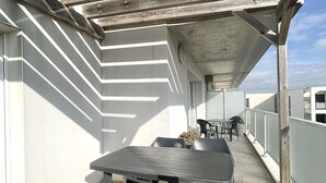 Une terrasse extérieure avec une table et des chaises, une pergola en bois et des plantes en pot.