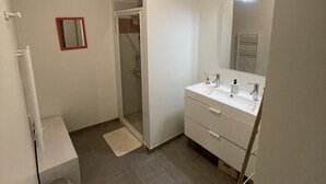 Une salle de bain équipée d’une douche, d’un lavabo, d’un miroir et de toilettes.