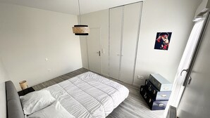 Une chambre à coucher avec un lit, une armoire et une affiche accrochée au mur.