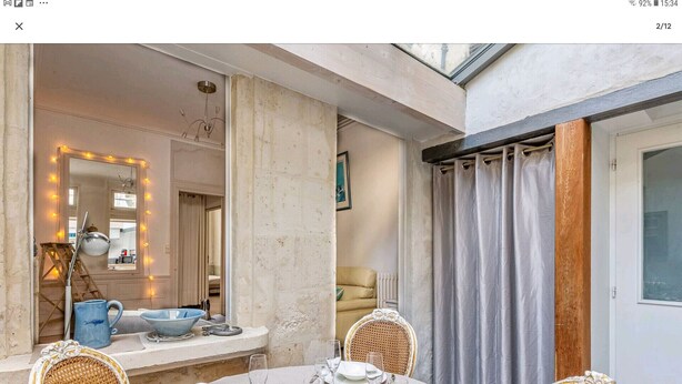 A dining area with a table set for four, a mirror with lights, and a view of the outside.