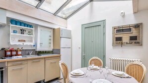 A compact kitchen with a dining area, featuring a built-in oven, a refrigerator, and a dining table set for four.