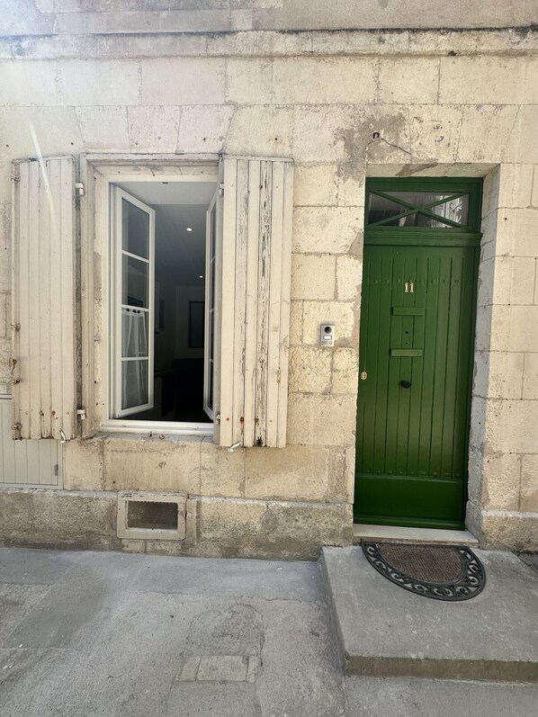 Ein Gebäude mit einer grünen Tür und einem Fenster mit Holzklappläden.