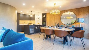 A modern kitchen with a central island, wooden accents, and a dining area with a round table and chairs. - More Mountain  - Demi Lune. Central Morzine location and less than 2 minutes walk to main ski lifts, bars and restaurants. (Morzine)