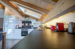 A modern kitchen with a central island, built-in appliances, and a skylight.