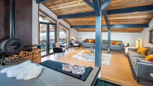 Un amplio salón con techo alto, vigas de madera y ventanas grandes.