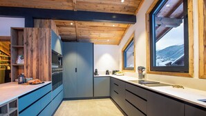 Una cocina moderna con techo de madera, armarios empotrados y un amplio ventanal con vistas a un paisaje nevado.