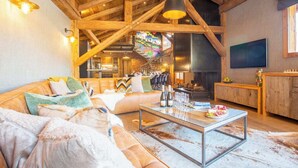 Un salón espacioso con techo alto, un conjunto de sofás, una mesa de centro y una chimenea.