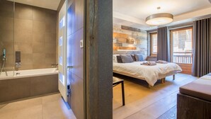 Un baño moderno con bañera y ducha, un dormitorio con cama y vistas al exterior.