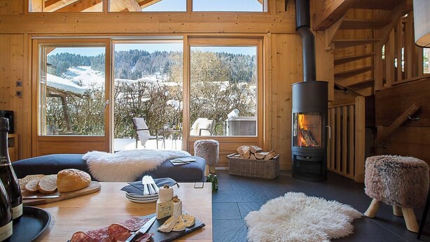 A cozy room with a fireplace, a dining table with food, and a view of a snowy landscape. - More Mountain - Chalet Jirishanca in central Morzine with Outdoor Jacuzzi. Large split level chalet less than 2 minutes walk to ski lifts & bars. (Morzine)