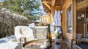 A wooden cabin with a dining area featuring a grill, wine bottle, and glasses. - More Mountain - Chalet Jirishanca in central Morzine with Outdoor Jacuzzi. Large split level chalet less than 2 minutes walk to ski lifts & bars. (Morzine)
